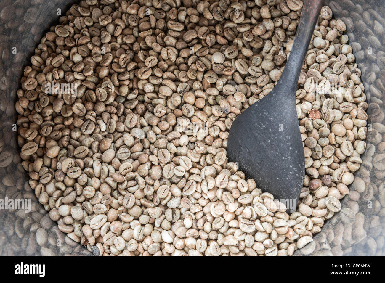 Chicchi verdi di caffè nella canna con una vecchia ciotola di legno, pronti per essere arrostiti. Foto Stock