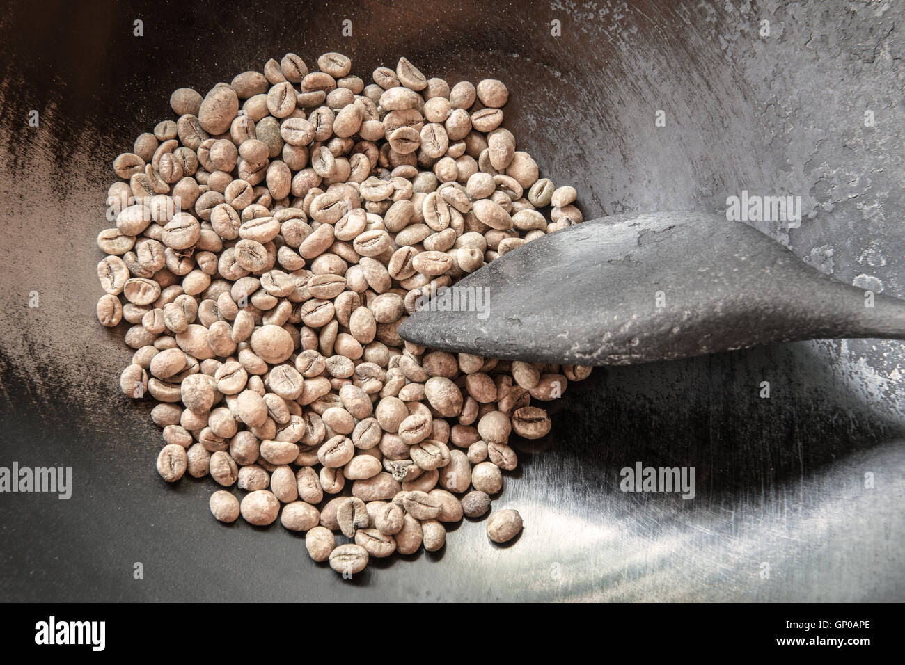 Chicchi verdi di caffè in padella con una vecchia ciotola di legno, pronti per essere arrostiti. Foto Stock