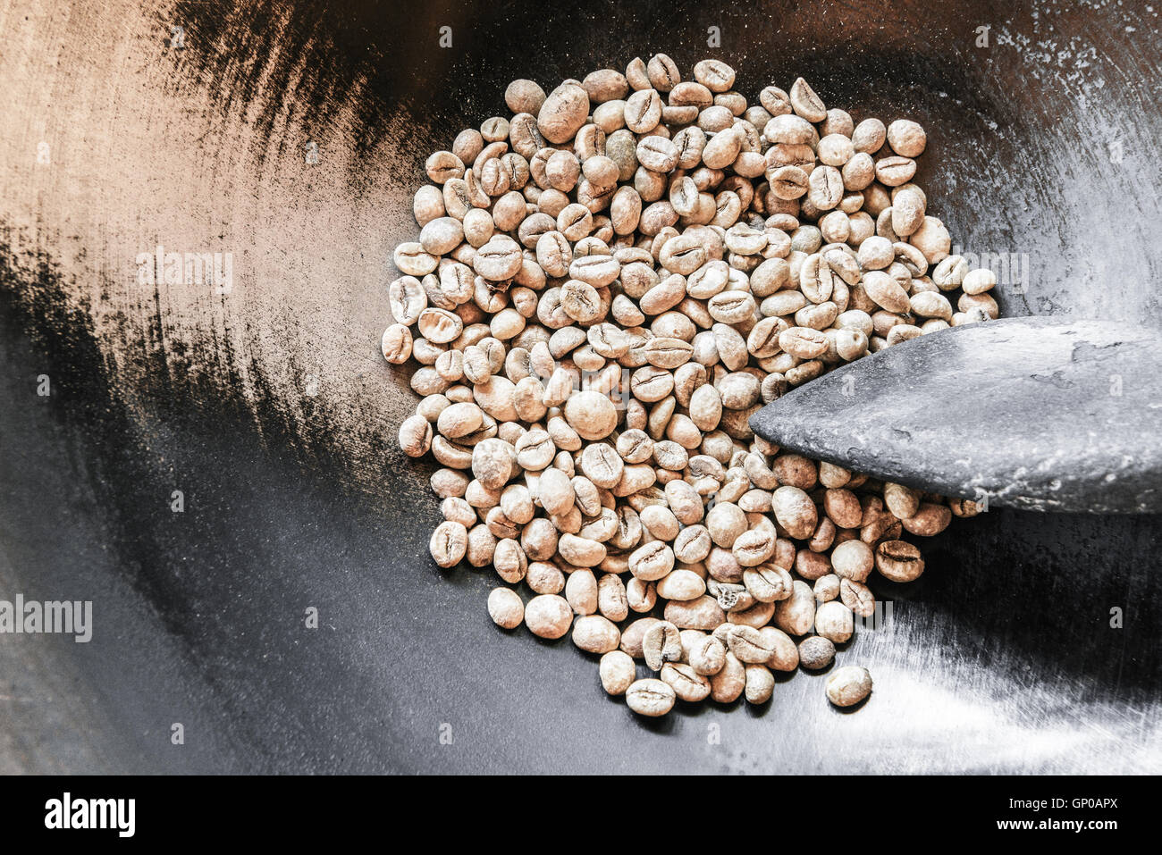 Chicchi verdi di caffè in padella con una vecchia ciotola di legno, pronti per essere arrostiti. Copia dello spazio. Foto Stock