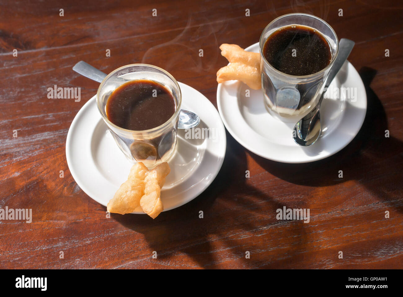 Tradizione Thai caffè caldo con latte condensato zuccherato in vecchio stile di coppa, servita su un tavolo di legno. Foto Stock