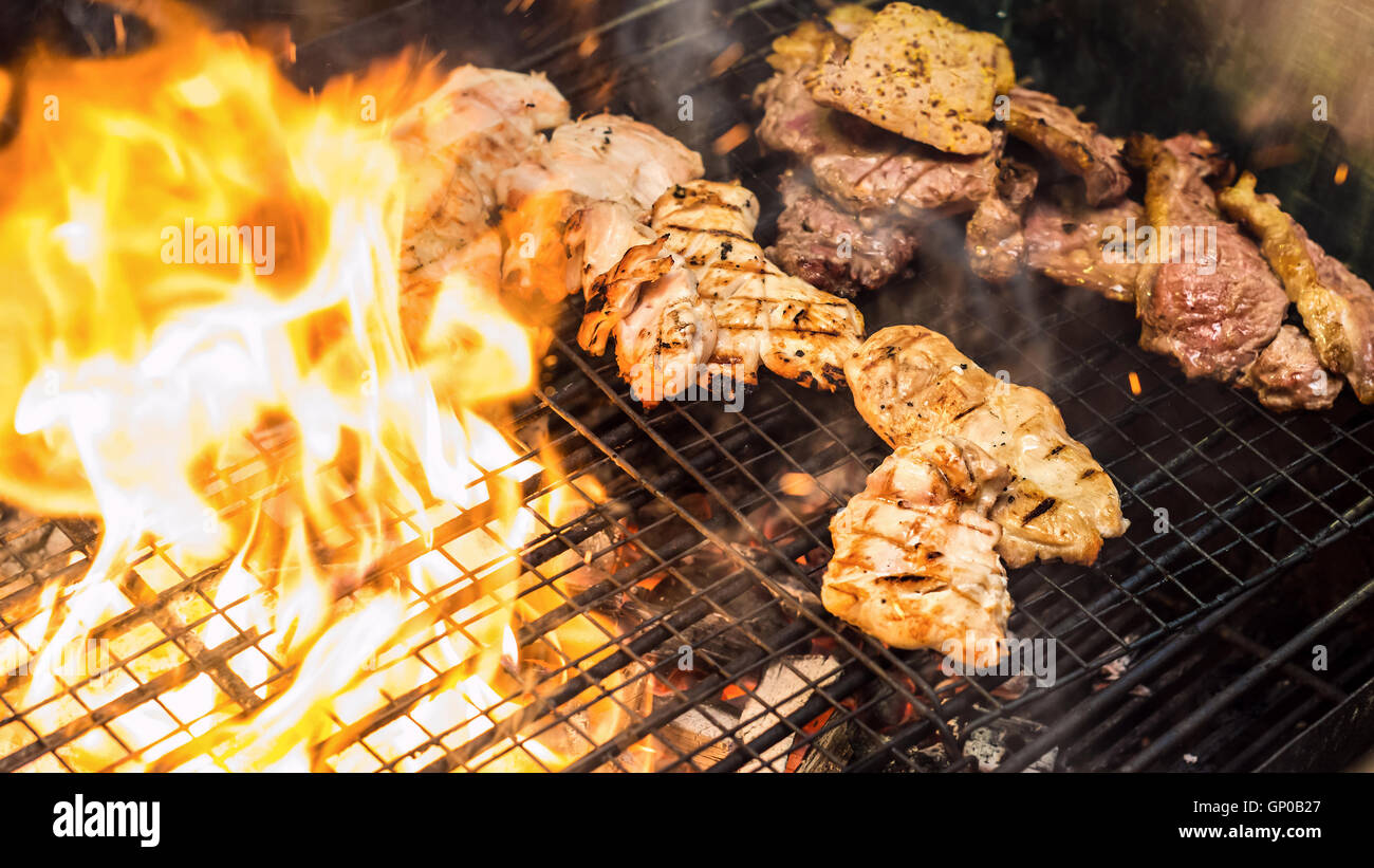 Un assortimento di deliziose grigliate di carne sopra la fiamma su un barbecue Foto Stock