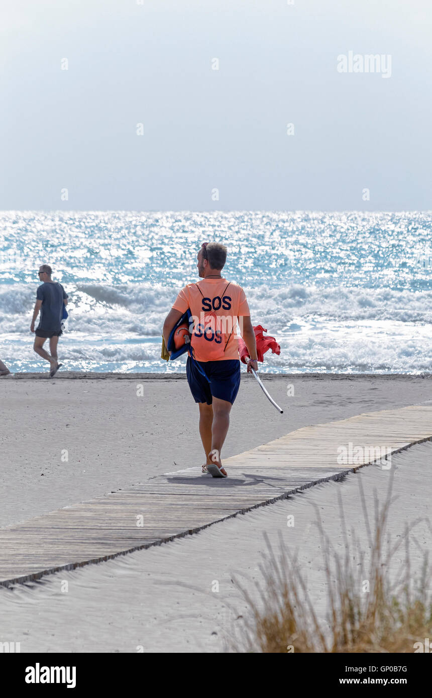 Bagnino andando al posto di osservazione con la bandiera rossa in mano. Divieto di nuotare in spiaggia di Castellon de la Plana Foto Stock