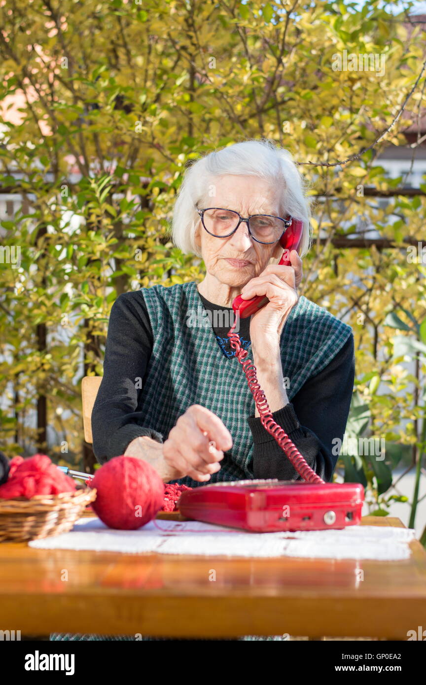 Donna anziana con il telefono nel cortile posteriore Foto Stock
