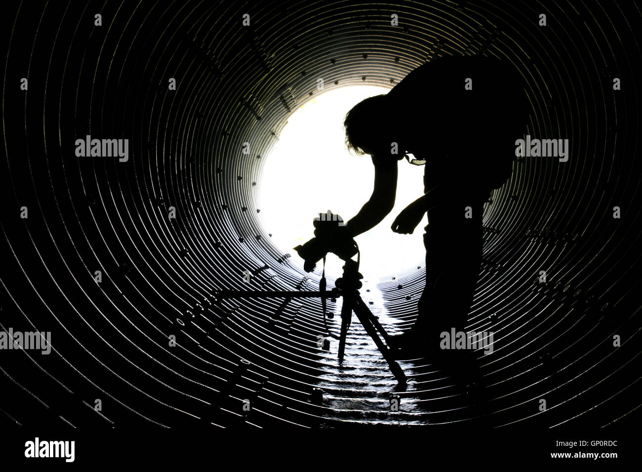 "Nel tunnel della fotografia", una silhouette di un fotografo in un tunnel di drenaggio Foto Stock