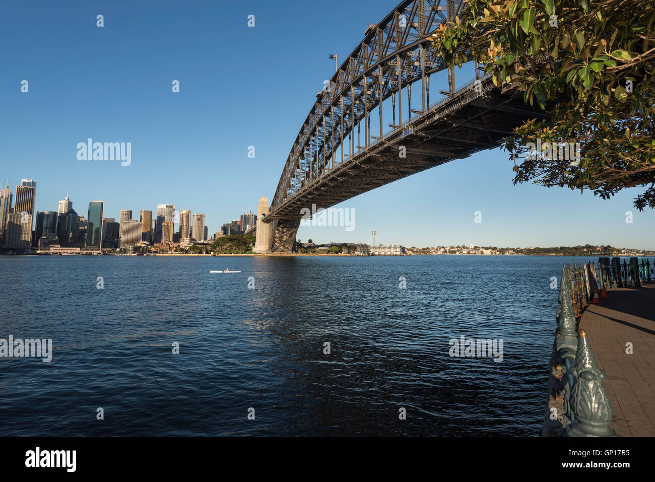 Un kayak di prima mattina che si addica sotto il Sydney Harbour Bridge in Australia verso la parte orientale del porto Foto Stock