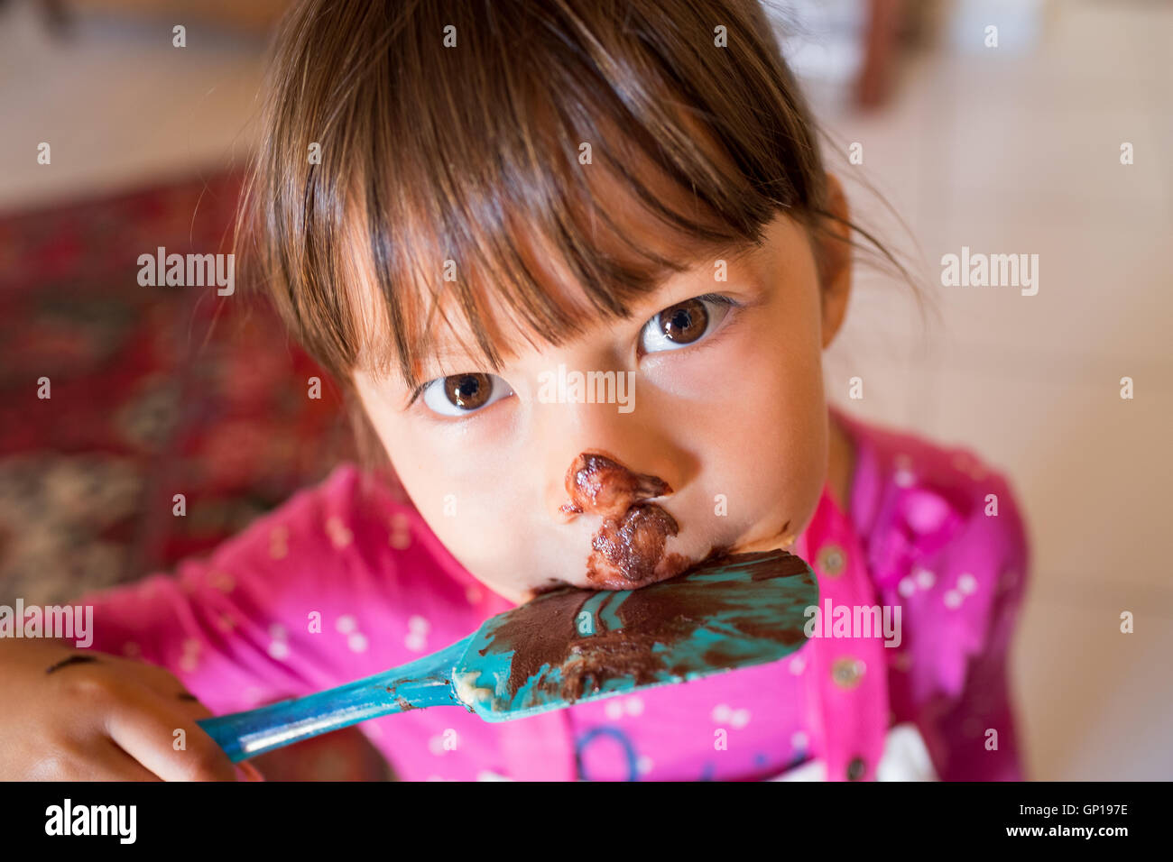 Ragazza giovane mangiare una spatola piena di cioccolato Foto Stock