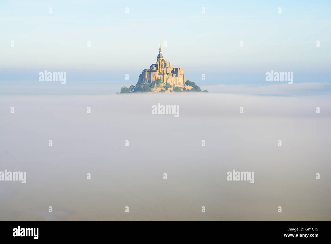 VISTA AEREA. Abbey su un picco isolato sopra la nebbia di mattina presto. Mont Saint-Michel, Manica, Normandia, Francia. Foto Stock