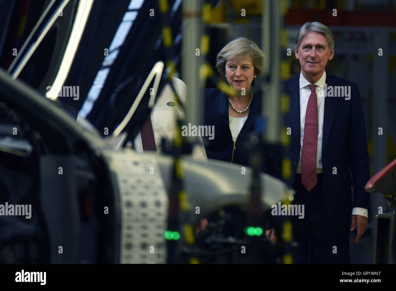 Il primo ministro Theresa Maggio parla con il Cancelliere dello Scacchiere, Philip Hammond visualizzare un auto linea di produzione durante una visita alla Jaguar Land Rover in fabbrica a Solihull dove ha utilizzato la visita per evidenziare che la Gran Bretagna continua a essere aperto per investimento economico a seguito del paese la decisione di lasciare l'Unione europea. Foto Stock