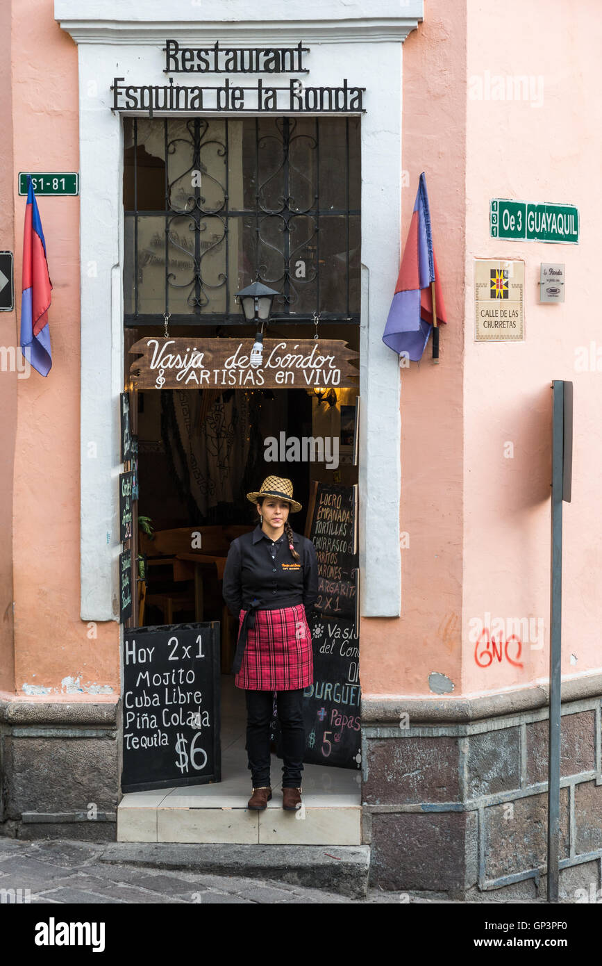 Una giovane donna in piedi di fronte a un ristorante nella storica città vecchia, Quito, Ecuador. Foto Stock