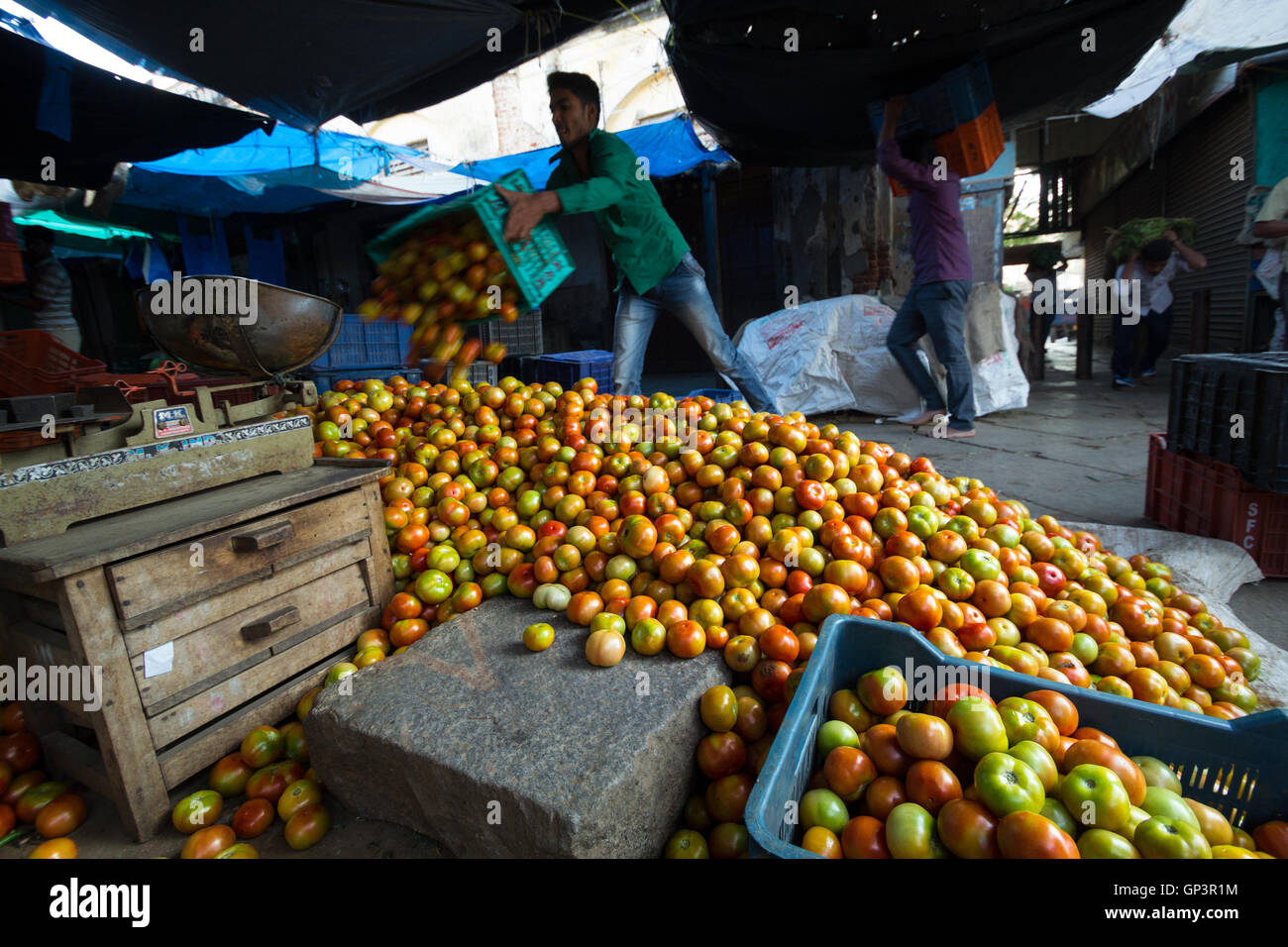 Carico di testa i lavoratori di scarico sacchi veget nel mercato Devaraja a Mysore, India. Lo scarico di pomodori. Foto Stock