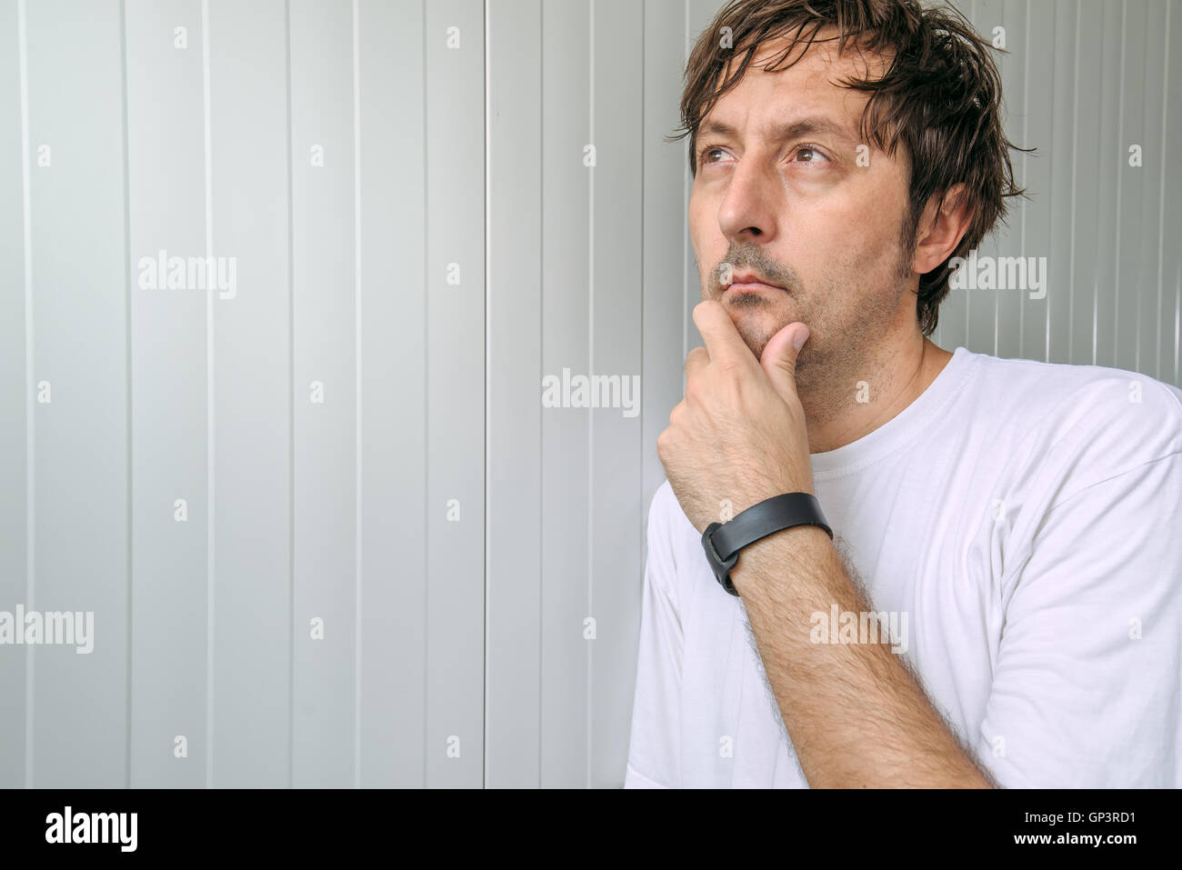 L'uomo con la mano sul mento pensando pensieri profondi e rendendo le decisioni difficili Foto Stock