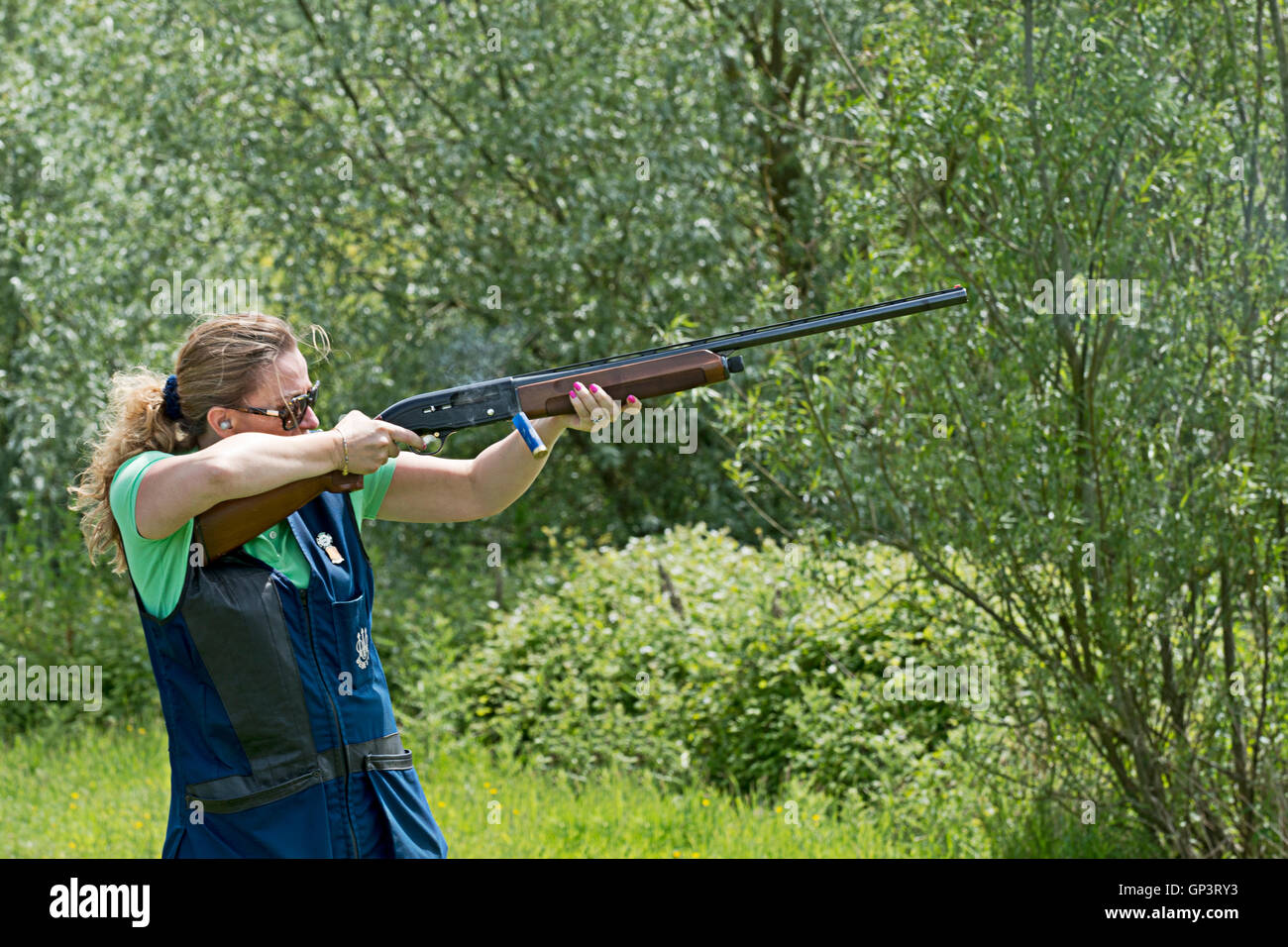 Una femmina di tiro piccioni di argilla con un fucile automatico. Foto Stock