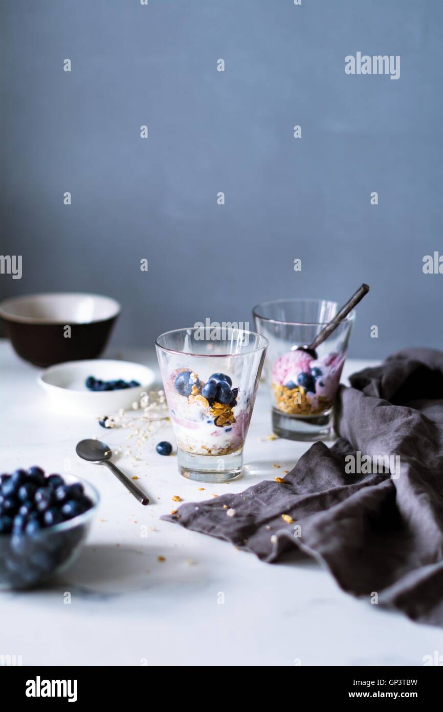 Sana parfait di colazione con muesli fatti in casa, yogurt e mirtilli su una tavola di marmo. Tonica immagine. Alimentare la vita ancora Foto Stock