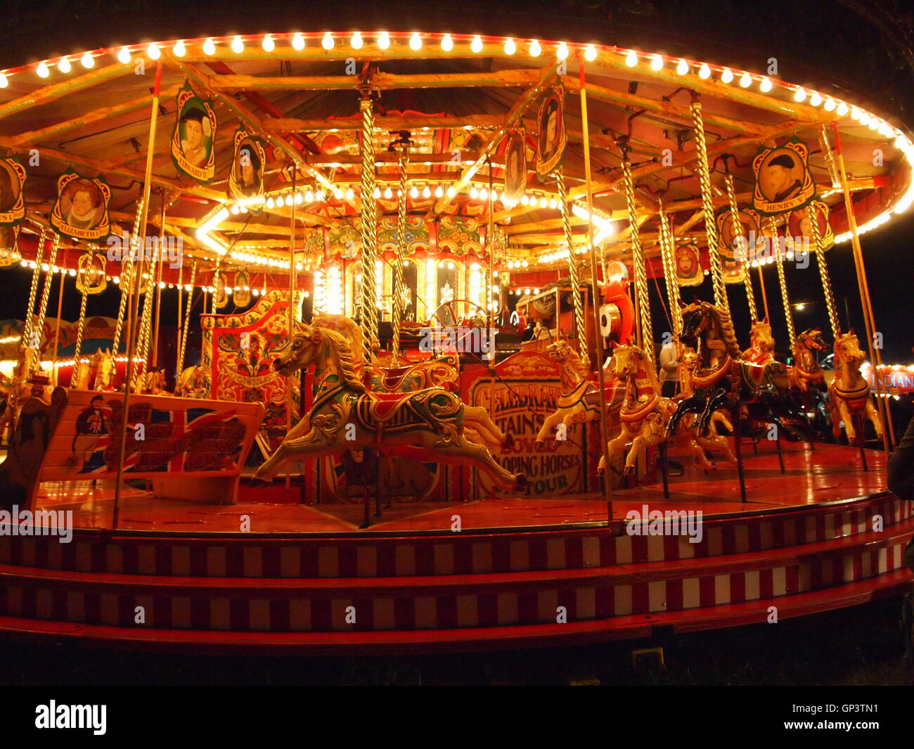 Il vapore Gallopers illuminata di notte, vapore fiera del divertimento, luna park, cavalli tre profondi Foto Stock