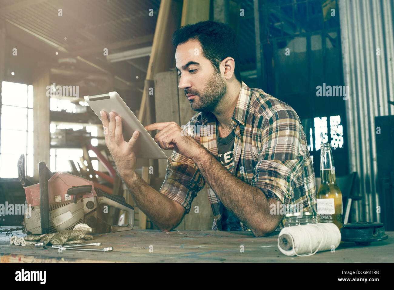 Uomo in officina con tavoletta digitale per accedere fai-da-te le istruzioni di riparazione su internet Foto Stock