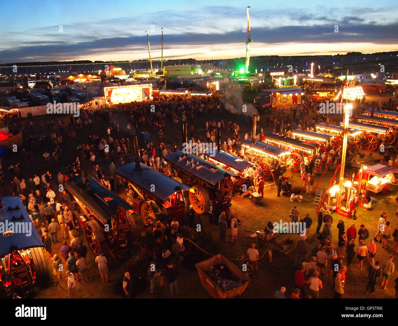 Grande Dorset Fiera a vapore di notte guardando verso il basso sulla Showmans motori di trazione tutto illuminato e la gente guardando intorno Foto Stock