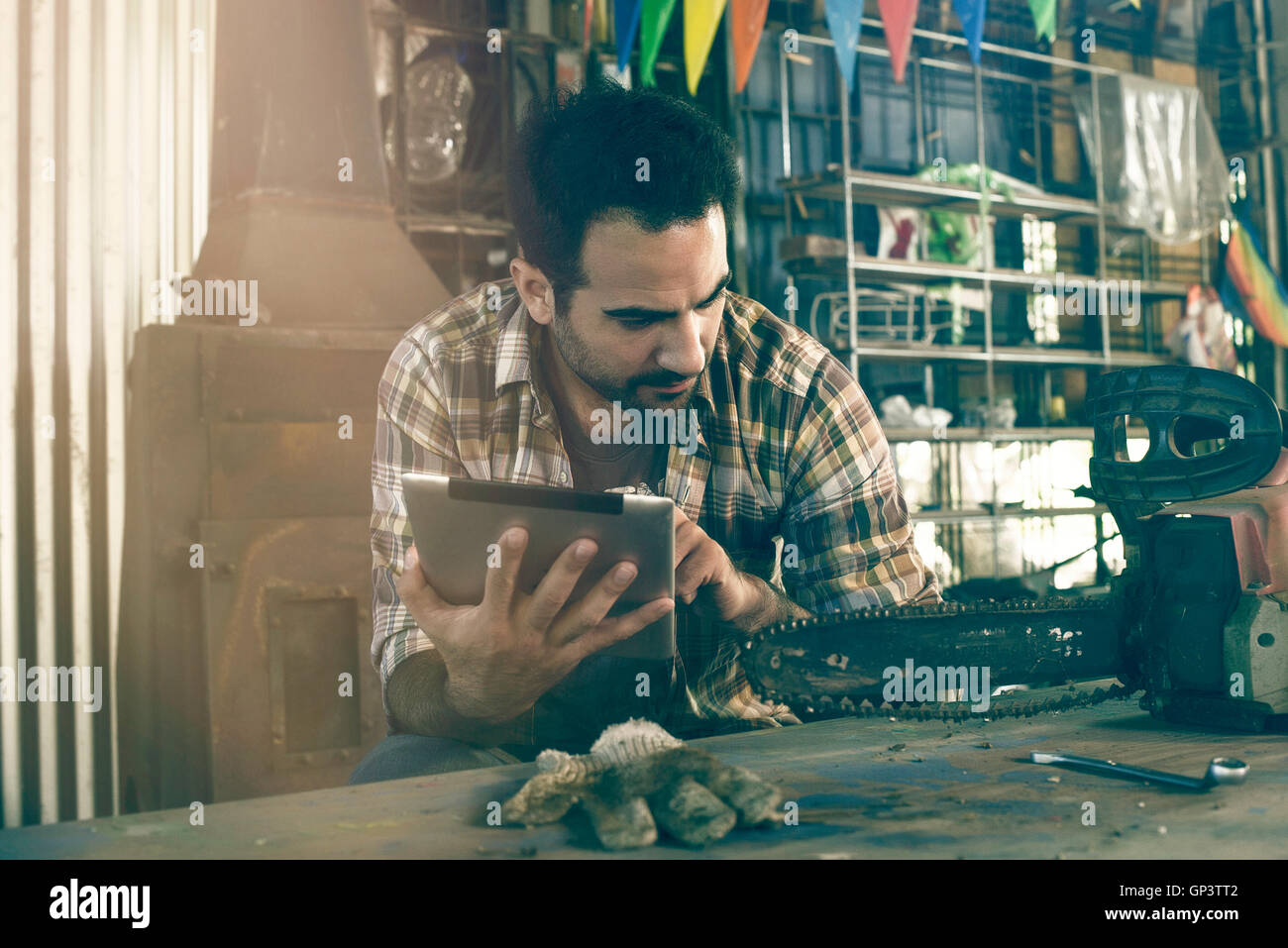 L'uomo fa riferimento chainsaw istruzioni di riparazione sulla tavoletta digitale Foto Stock