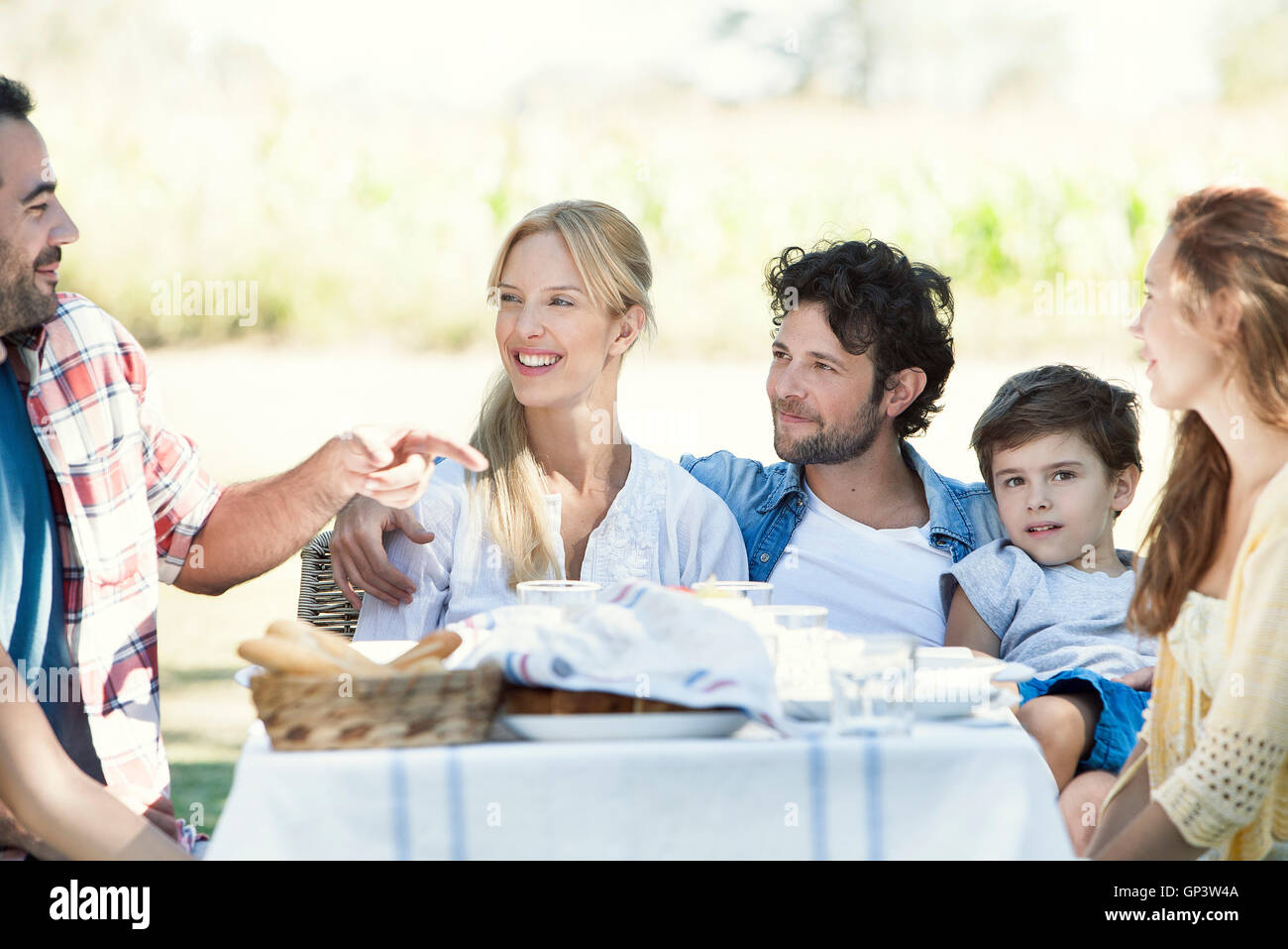 Famiglia estesa pasto mangiare e parlare insieme all'aperto Foto Stock