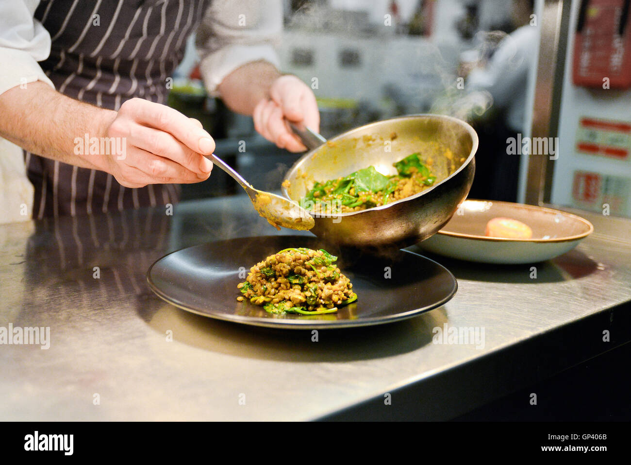 Ristorante lo chef immissione cotto piatto di lenticchie su piastra Foto Stock