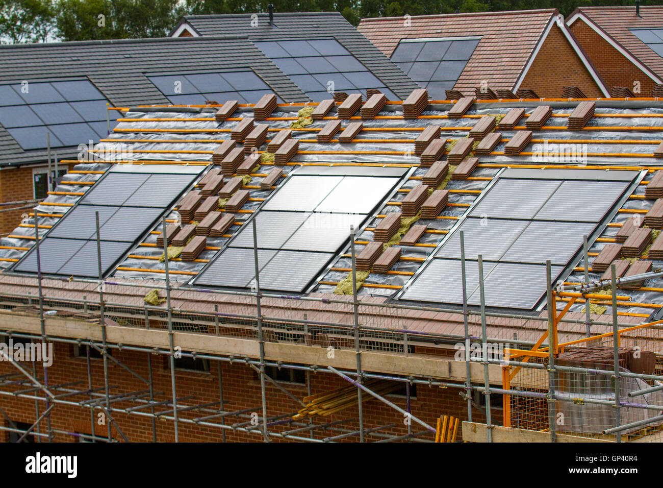 Redrow plc costruttori di case inglesi di proprietà; nuove case in costruzione, piccole case a efficienza energetica con tegole tetto pannelli solari integrati, o pannelli solari nel tetto su installazioni piastrellate casa in via di completamento, uno sviluppo a Buckshaw Village, vicino a Chorley, Lancashire, Regno Unito. Foto Stock