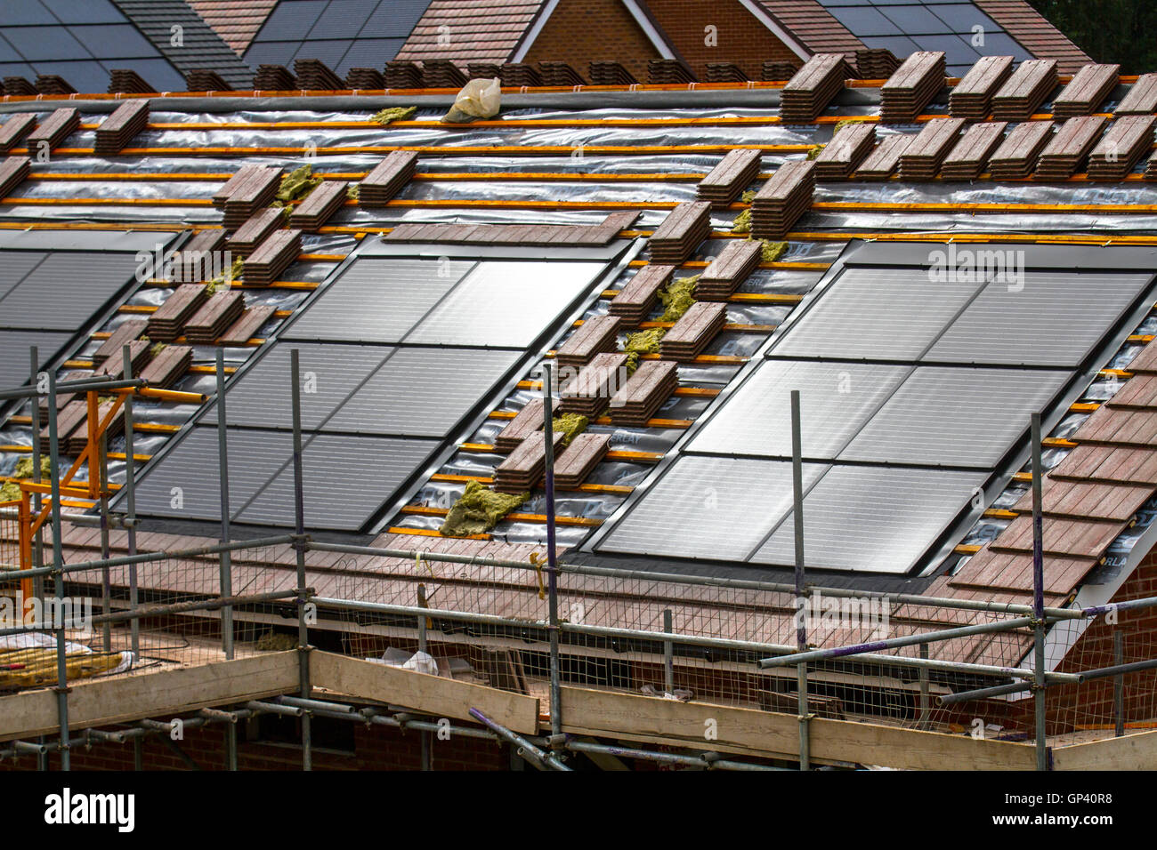 Redrow plc costruttori di case inglesi di proprietà; nuove case in costruzione, piccole case a efficienza energetica con tegole tetto pannelli solari integrati, o pannelli solari nel tetto su installazioni piastrellate casa in via di completamento, uno sviluppo a Buckshaw Village, vicino a Chorley, Lancashire, Regno Unito. Foto Stock