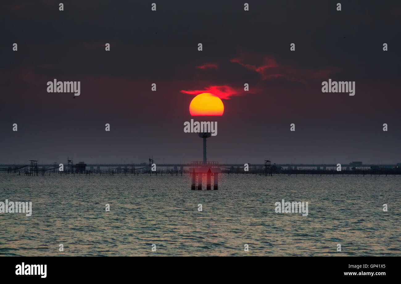 Parzialmente nuvoloso tramonto sul mare di riflessione. Foto Stock