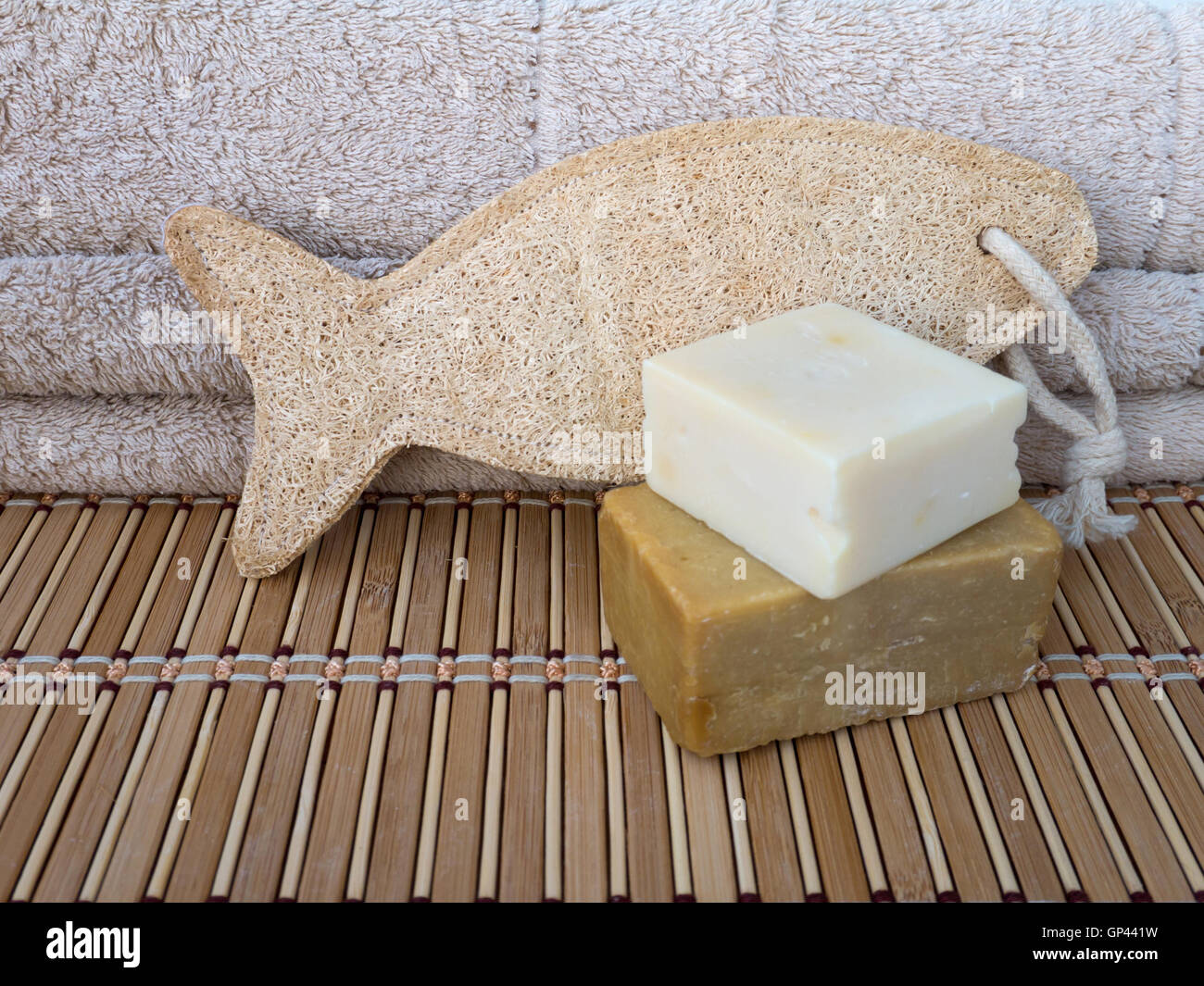 Sapone casalingo bar, loofah spugna in forma di pesce e asciugamani in spugna sul tappetino di bambù Foto Stock