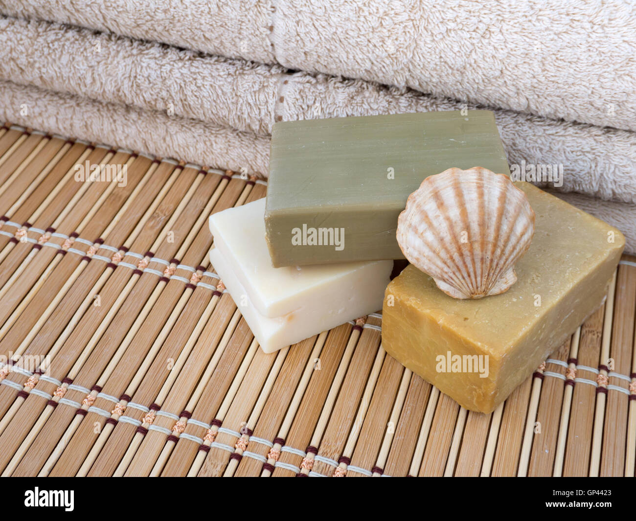 Tre Sapone casalingo bar, capesante shell e asciugamani in spugna sul tappetino di bambù Foto Stock