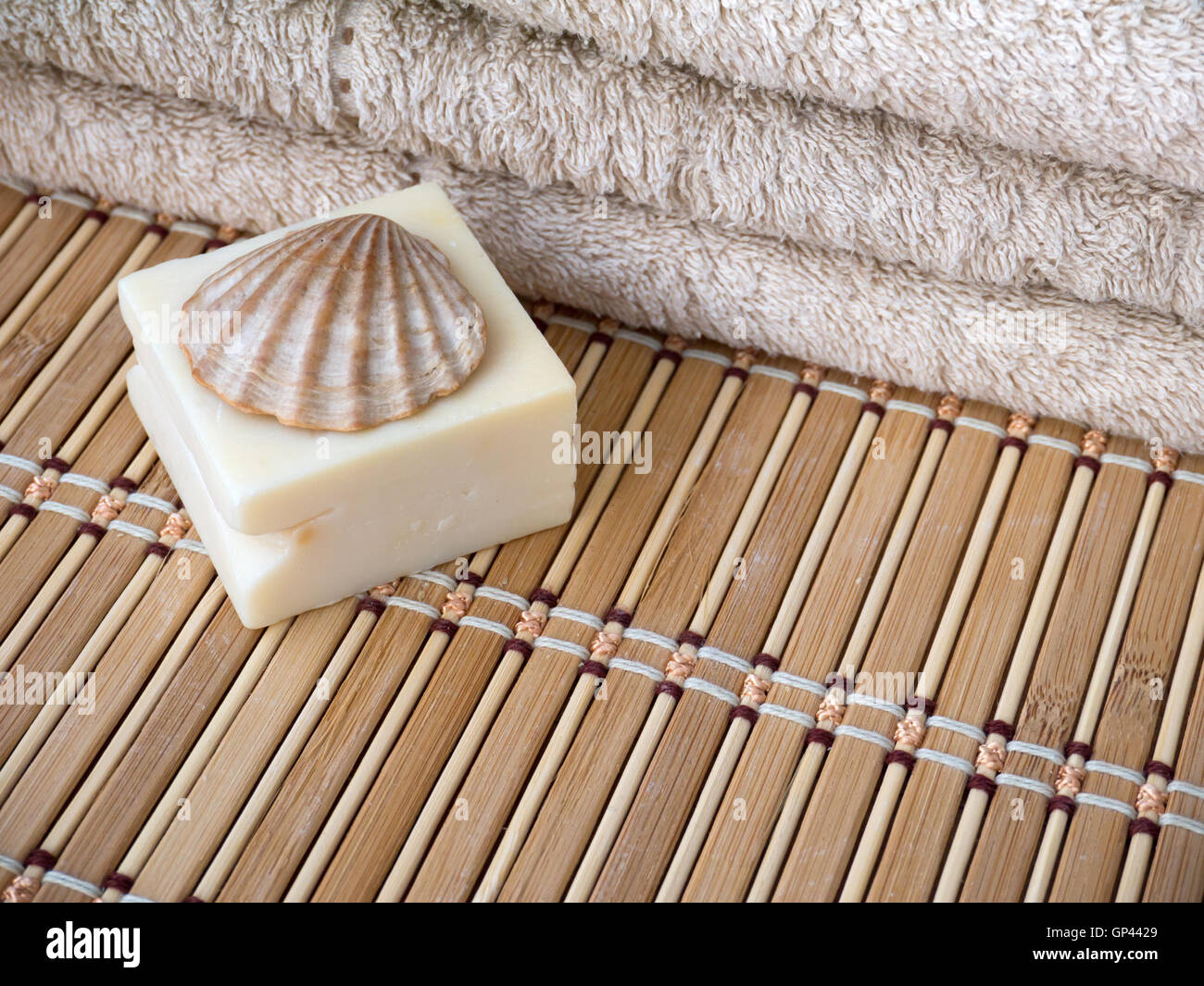 Latte naturale saponetta, capesante shell e asciugamani in spugna sul tappetino di bambù Foto Stock