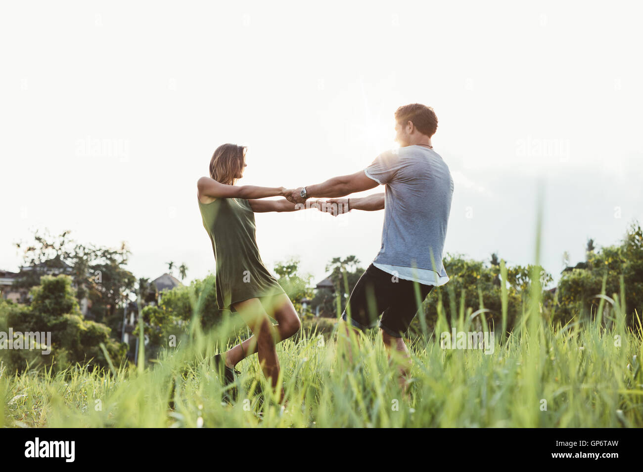Colpo di amare giovane coppia danzante in un campo di erba alta. L uomo e la donna per mano e balli all'aperto nel prato. Foto Stock