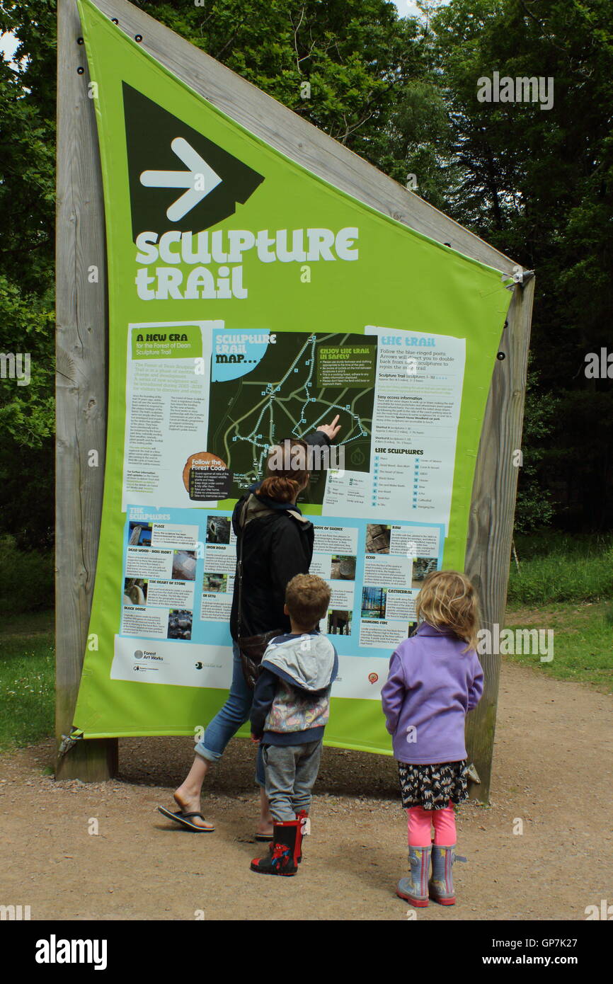 I visitatori di leggere la scheda di informazioni all'inizio del sentiero delle sculture nella Foresta di Dean, Beechenhurst, Gloucesterhire Foto Stock