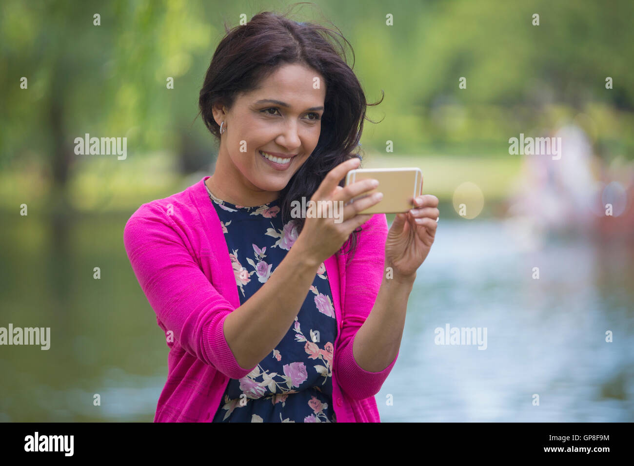 Felice donna ispanica utilizzando il suo telefono cellulare in un parco Foto Stock