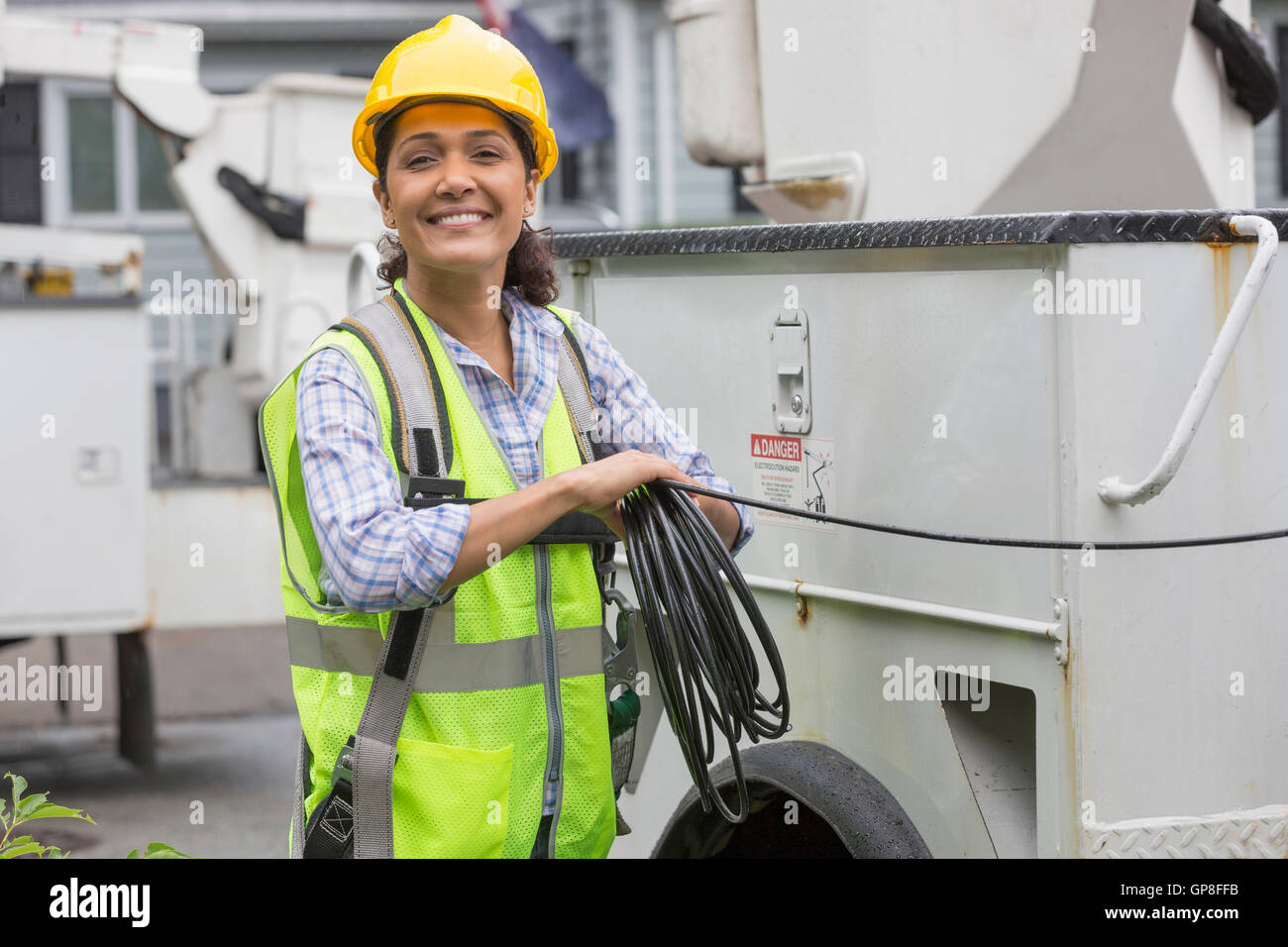 Ritratto di felice ispanica utility femmina lavoratore cavo di contenimento da autocarro presso il sito Foto Stock