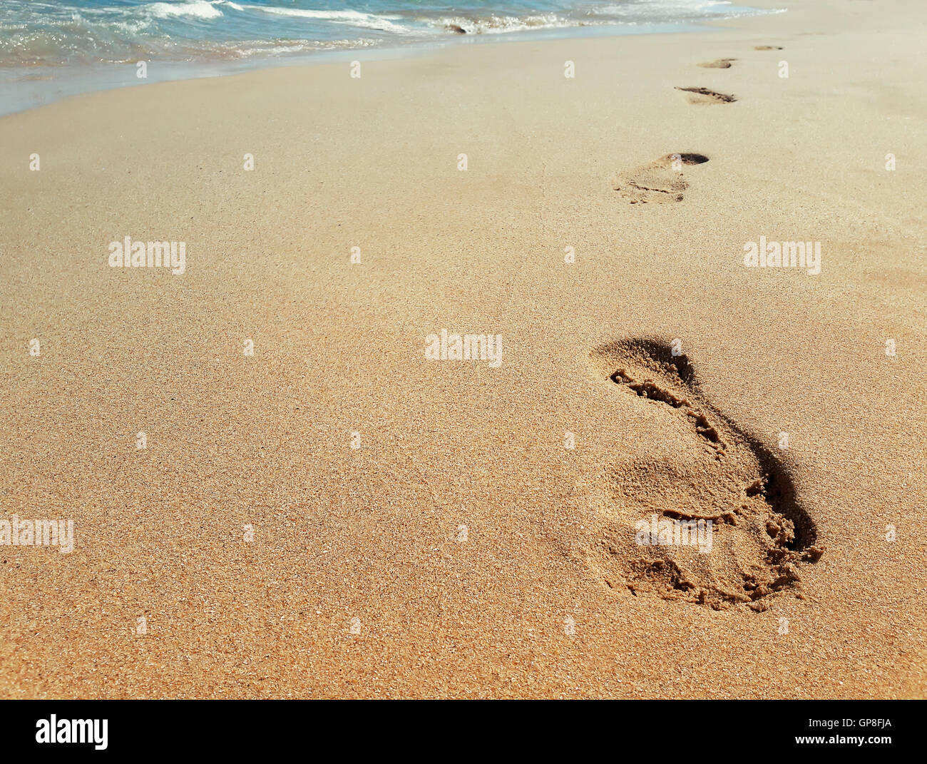 Primo piano di orme nella sabbia in spiaggia vicino all'acqua. Il concetto di viaggio Foto Stock