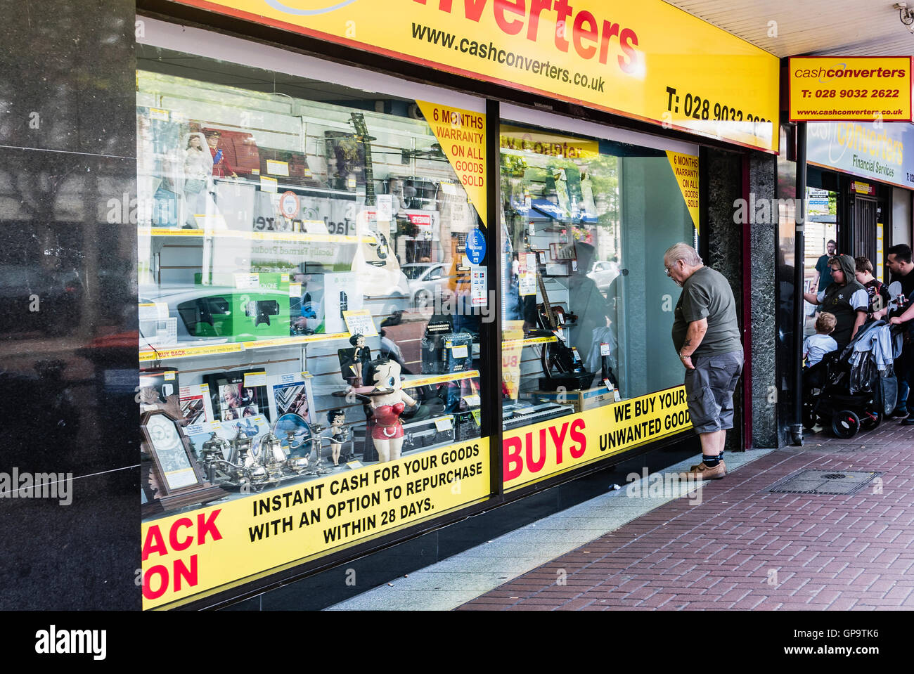 Le persone che cercano nella finestra di un convertitori Cash Shop. Foto Stock