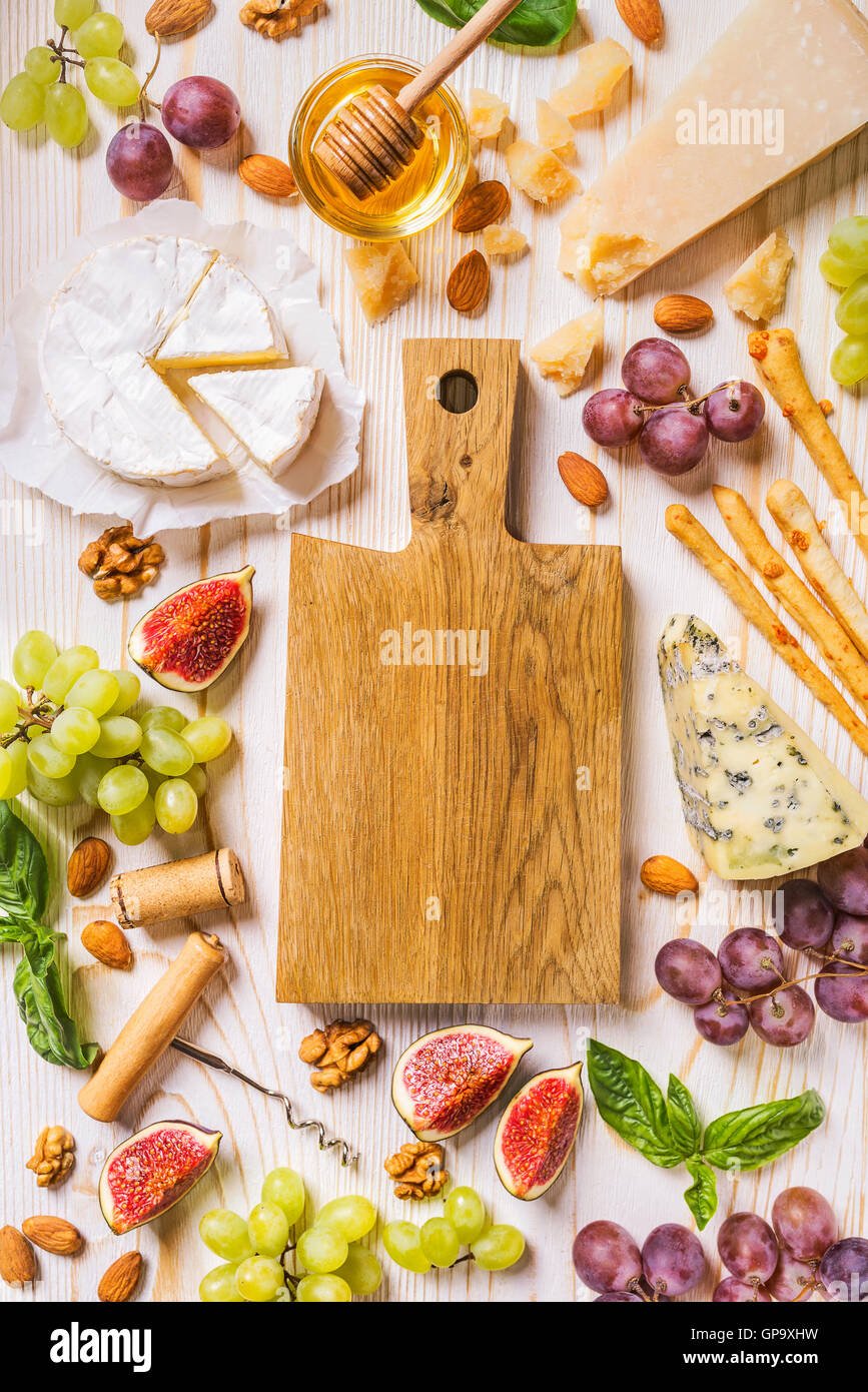Un vassoio di formaggi con frutta e miele sul legno ruvido Foto Stock
