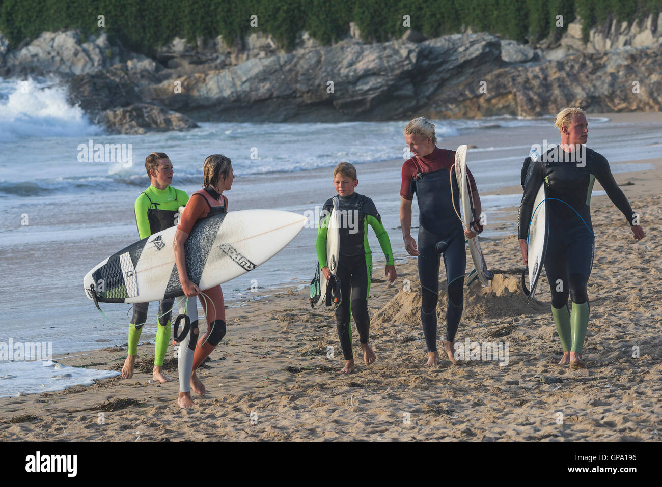 Un gruppo di cinque giovani Cornish surfers da Newquay terminare la loro sessione di surf a Fistral in Newquay, Cornwall. Regno Unito. Foto Stock