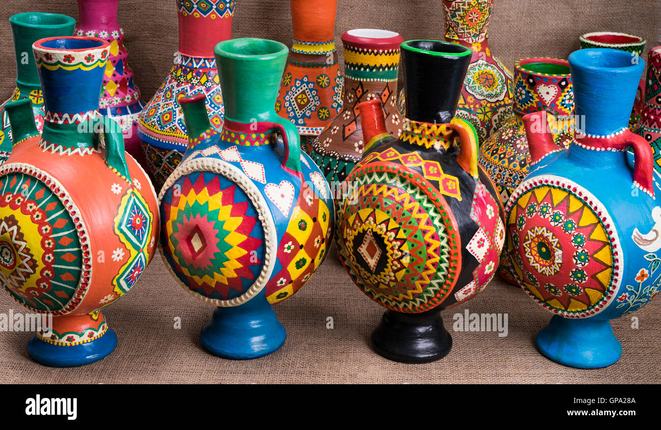 Ancora la vita di quattro decorate colorate ceramiche artigianali brocche su un letto di sacco sullo sfondo Foto Stock