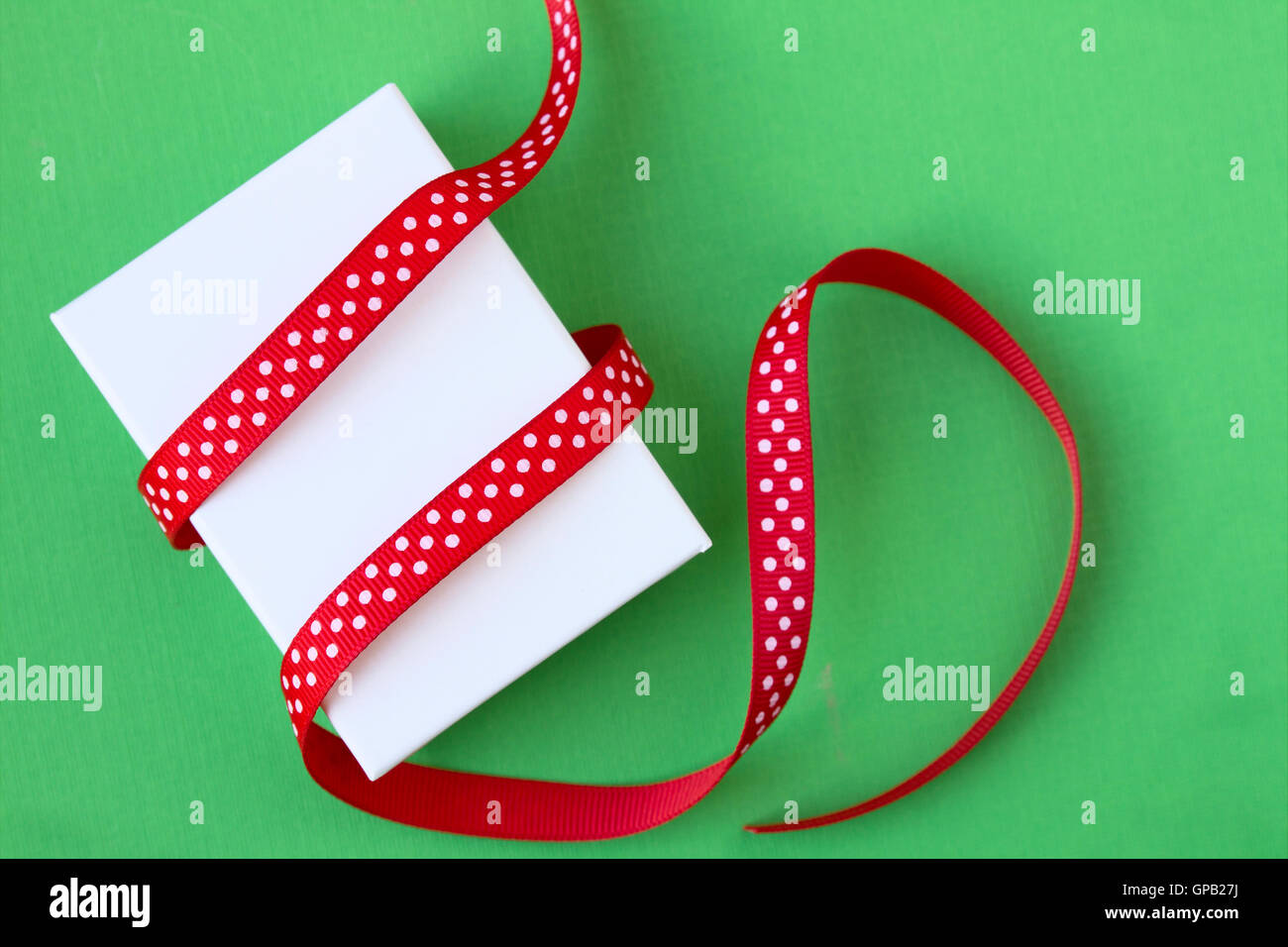 Piccolo regalo di Natale scatola e nastro su sfondo verde Foto Stock