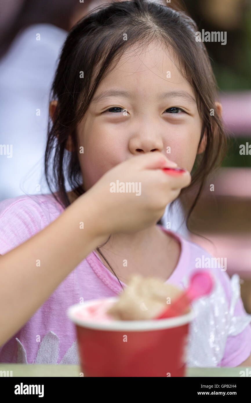Kid a mangiare il gelato con la faccia felice. Foto Stock