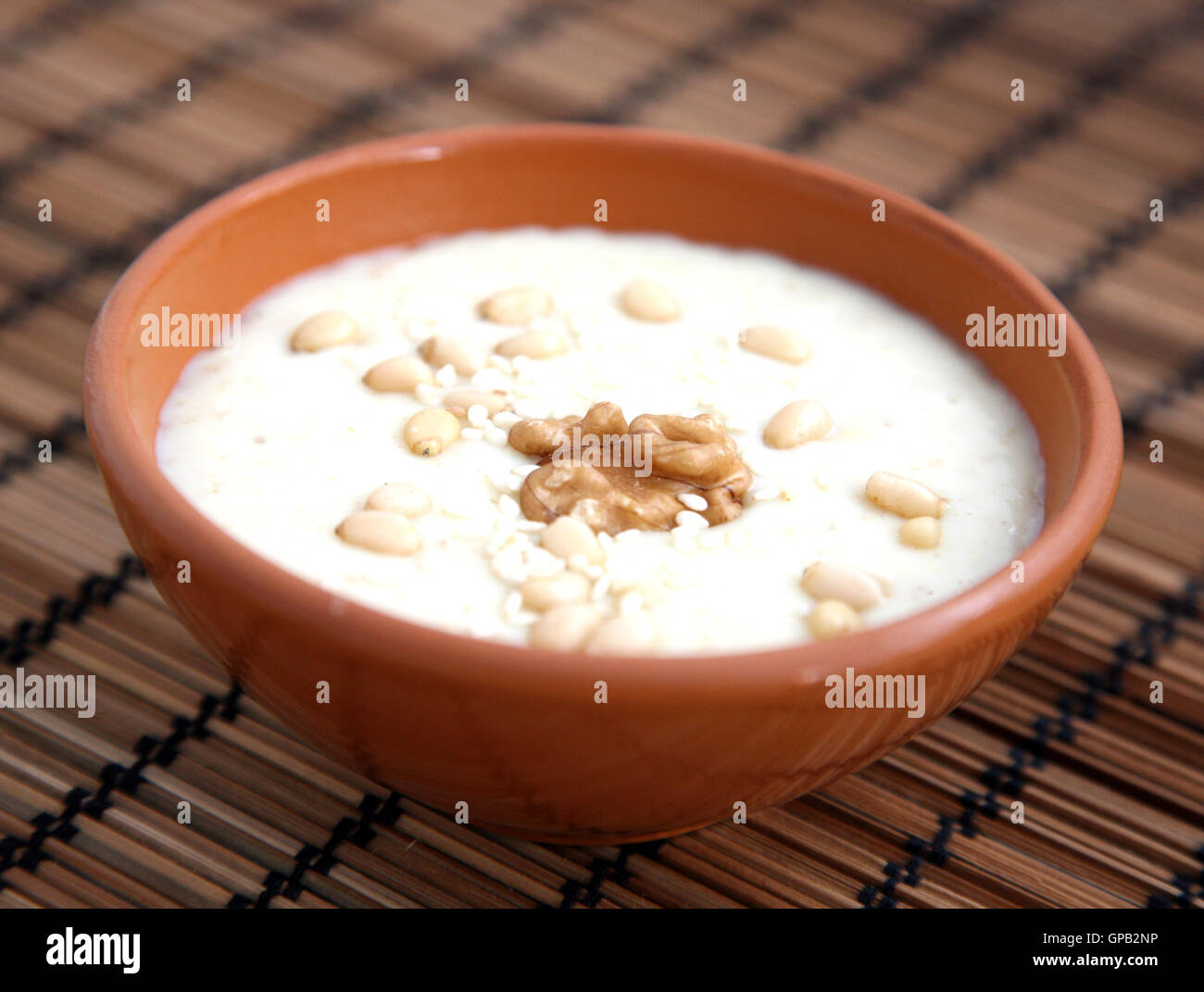 Farina di avena porridge con semi di sesamo, noci e pinoli marrone sul tappetino di bambù Foto Stock