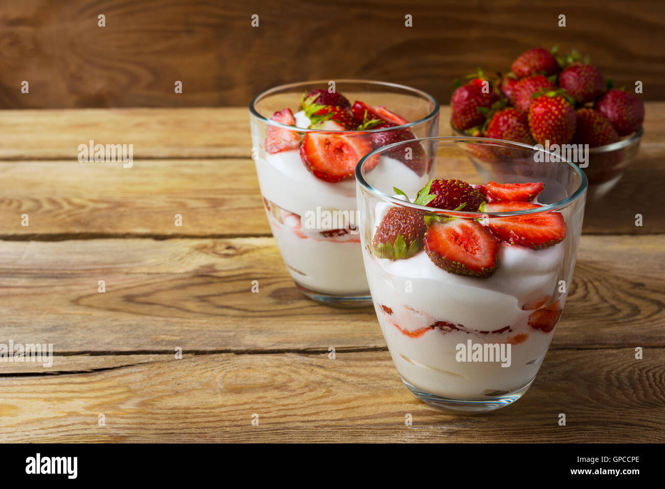 Layered fragola dessert su sfondo di legno. La dieta yogurt dessert con fragole mature. Foto Stock
