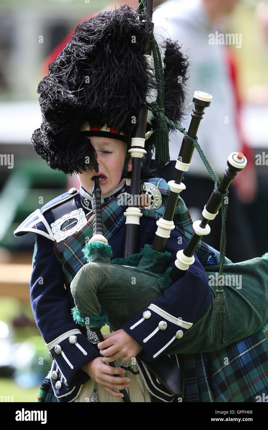 Un giovane membro dell'Ballater Pipe Band lotte nel vento a Braemar Royal Highland Gathering al Princess Royal e il Duca di Fife Memorial Park, Braemar, che è frequentato dalla Regina come patrono. Foto Stock