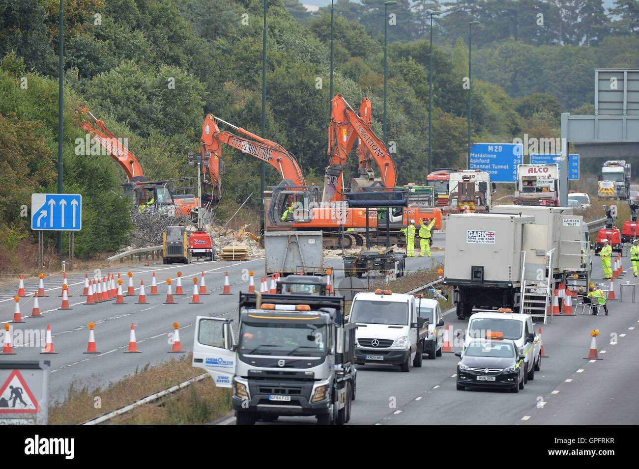 Lavoratori di demolizione di rimuovere la restante struttura del danneggiamento di una passerella oltre l'autostrada M20 nel Kent, che è stata chiusa in entrambe le direzioni per consentire le autostrade in Inghilterra per svolgere il lavoro. Foto Stock