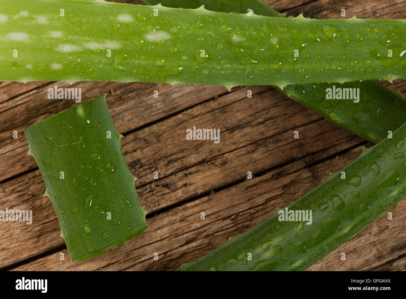 Aloe vera verde bagnato fresche foglie tagliate a fette decorate sulla scrivania in legno. Foto Stock