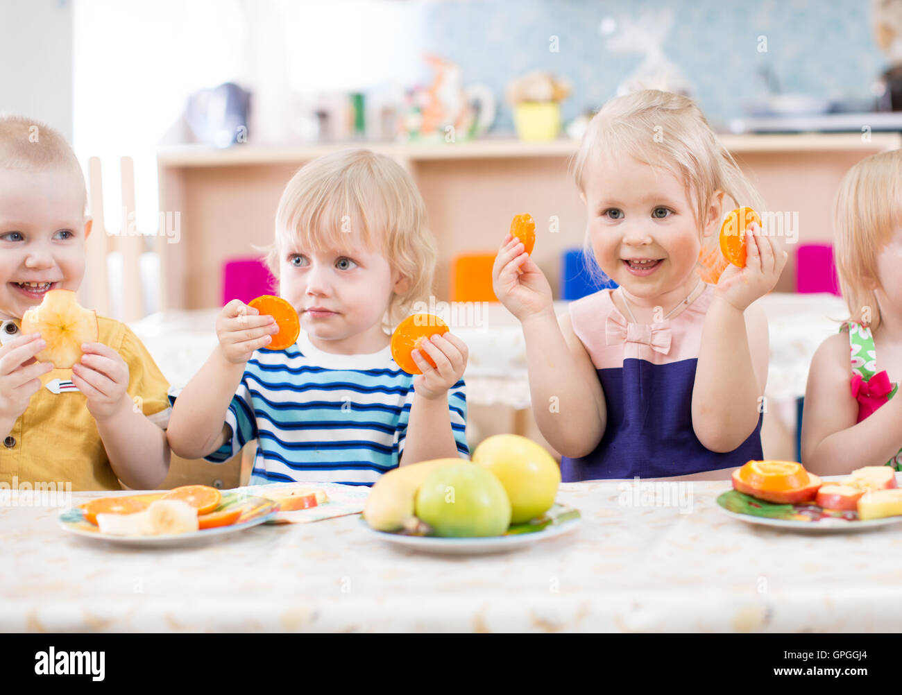 Funny kids mangiare frutta nella scuola materna di sala da pranzo Foto Stock