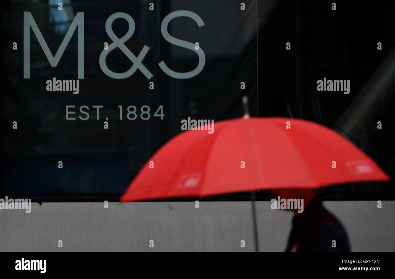 Un uomo che porta un ombrello passeggiate segnaletica in passato presso la sede dei marchi &AMP; Spencer a Londra, come la società è tagliare circa 500 posti di lavoro presso la sua sede, secondo le relazioni. Foto Stock