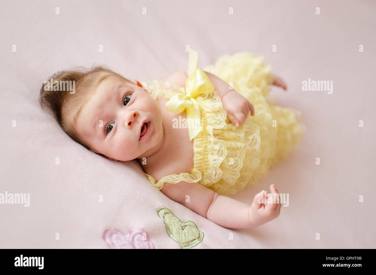 Adorabili due mesi bambina sdraiata su una coperta rosa Foto Stock