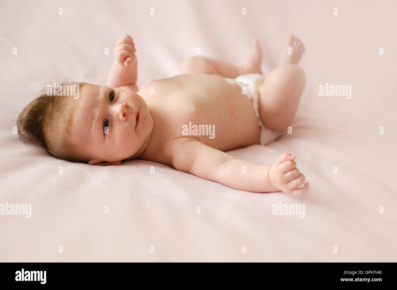 Adorabili due mesi bambina sdraiata su una coperta rosa Foto Stock