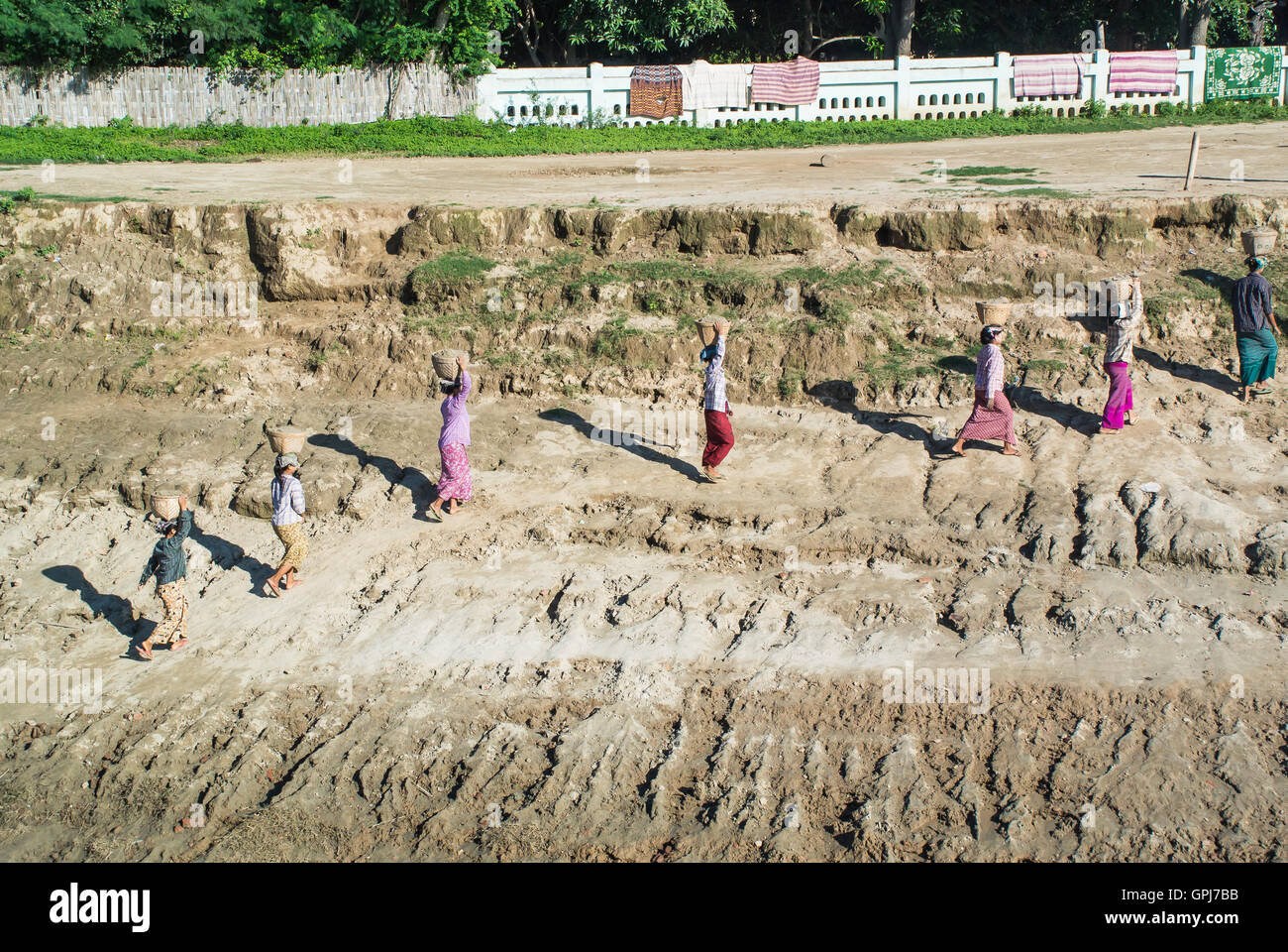 Le donne del villaggio di argilla che porta dal bordo del fiume alla sommità della banca Foto Stock